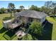 Backyard view featuring a spacious deck with a hot tub, patio with a fire pit, and lush landscaping at 8437 Indies Dr, Hudson, FL 34667