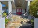 Exterior close-up of a welcoming red double door with stone steps and lush plants at 8437 Indies Dr, Hudson, FL 34667