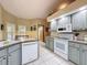 Well-lit kitchen featuring white appliances, light blue cabinets, and neutral-toned walls and tile flooring at 8437 Indies Dr, Hudson, FL 34667