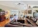 Open living room with ceiling fan, wood floors, leather sofa, and view to the sunroom and kitchen at 8437 Indies Dr, Hudson, FL 34667