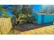 An exterior view of a shed with a blue door, surrounded by mature trees and a wood fence at 860 16Th S Ave, St Petersburg, FL 33701