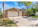 Exterior angle of home showing 3 car garage and large driveway with palm trees in yard at 8746 Tantallon Cir, Tampa, FL 33647