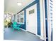 Inviting front porch with blue siding, a white front door, and comfortable turquoise seating at 8909 N Dexter Ave, Tampa, FL 33604