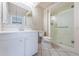 Bathroom featuring floral wallpaper, glass shower, and white tile floor at 9214 Mission Oaks Blvd, Seminole, FL 33776