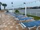 Blue lounge chairs line a pool deck with string lights, overlooking a waterfront and community buildings at 10351 Regal Dr # 18, Largo, FL 33774
