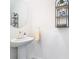 Bright and clean bathroom features a pedestal sink, round mirror, and a black metal shelf at 10727 Penny Gale Loop, San Antonio, FL 33576