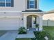 Home's entrance with a covered porch, an elegant front door, and landscaping at 10727 Penny Gale Loop, San Antonio, FL 33576