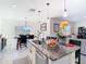 This kitchen has granite counters, stainless appliances, pendant lights, and an island with seating overlooking the dining and living areas at 10727 Penny Gale Loop, San Antonio, FL 33576