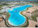 Wide aerial shot of the lagoon with an inflatable water park, beach areas, and cabana-style seating at 10727 Penny Gale Loop, San Antonio, FL 33576