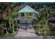 Light green coastal home featuring a white balcony and surrounded by palm trees at 112 13Th Ave, Indian Rocks Beach, FL 33785