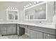 Bathroom with double vanity, marble counters, gray cabinets, and framed, lighted mirrors at 12304 Silton Peace Dr, Riverview, FL 33579