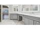 Bathroom featuring double vanity, marble counters, gray cabinets, and bright, lighted mirrors at 12304 Silton Peace Dr, Riverview, FL 33579