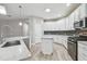 Well-lit kitchen with white cabinets, marble countertops, stainless steel appliances, and wood-look floors at 12304 Silton Peace Dr, Riverview, FL 33579
