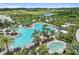 Aerial view of a sunny Florida community pool surrounded by landscaping and palm trees with ample seating at 29488 Ginnetto Dr, Wesley Chapel, FL 33543