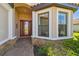 Home entrance with a red door, brick-paved walkway, stone veneer accents, and a charming bay window at 29488 Ginnetto Dr, Wesley Chapel, FL 33543