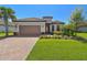Charming exterior of this home, featuring a red tile roof, brick driveway, and well-manicured lawn at 29488 Ginnetto Dr, Wesley Chapel, FL 33543