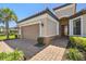 Exterior of a charming single-Gathering home featuring a two-car garage, brick-paved driveway, and lush landscaping at 29488 Ginnetto Dr, Wesley Chapel, FL 33543