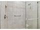 Close-up of a tiled shower with glass doors, safety bar, and built-in niche for toiletries at 29488 Ginnetto Dr, Wesley Chapel, FL 33543