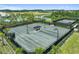 Aerial view of community tennis courts with a pool and lake surrounded by landscaping and palm trees in sunny Florida at 29488 Ginnetto Dr, Wesley Chapel, FL 33543