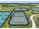 Aerial view of two tennis courts and three pickle ball courts surrounded by landscaping in a sunny Florida community at 29488 Ginnetto Dr, Wesley Chapel, FL 33543