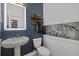 Stylish powder room with dark blue walls, an LED mirror, decorative art, and pedestal sink at 33105 Kateland Dr, Wesley Chapel, FL 33545