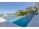 A refreshing, modern infinity pool overlooking a tranquil waterway and boat dock, framed by lush tropical landscaping at 3418 Overlook Ne Dr, St Petersburg, FL 33703