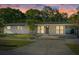 Well-lit single-story home with a covered carport, concrete driveway, and manicured front yard at sunset at 4105 W Iowa Ave, Tampa, FL 33616