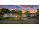 Well-lit single-story home with a covered carport, concrete driveway, and manicured front yard at sunset at 4105 W Iowa Ave, Tampa, FL 33616