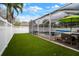 A screened-in backyard with turf, a privacy fence, and seating around a pool, making a relaxing and functional space at 513 Manns Harbor Dr, Apollo Beach, FL 33572