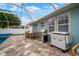 Outdoor patio with grill and dining furniture on a brick surface, partially covered for shade and comfort at 513 Manns Harbor Dr, Apollo Beach, FL 33572