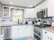 Well-lit kitchen featuring white cabinets, stainless steel appliances, and a charming window above the sink at 5433 Palmetto Rd, New Port Richey, FL 34652