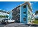 View of bright blue condo building featuring stone accent wall and reserved parking spot at 6201 2Nd E St # 89, St Pete Beach, FL 33706
