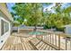 Wood deck overlooking a backyard pool with a safety fence and mature trees at 7323 Andre Dr, Zephyrhills, FL 33541