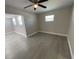 Bright bedroom featuring a ceiling fan, neutral walls, and gray wood-look flooring at 7323 Andre Dr, Zephyrhills, FL 33541