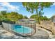 Backyard pool area with a safety fence, mature trees and a wood deck at 7323 Andre Dr, Zephyrhills, FL 33541