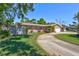 Landscaped yard and long driveway leading to this tan home with a two-car garage at 8243 37Th N Ave, St Petersburg, FL 33710