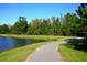 A curved walking path leads along the edge of a peaceful pond bordered by trees and green grass at 9314 Gladsome Dr, Land O Lakes, FL 34637