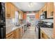 Galley kitchen with tile flooring, wood cabinets, stone countertops, and stainless steel appliances at 10034 64Th N Ave # 14, St Petersburg, FL 33708