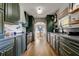 Modern kitchen featuring bold green cabinetry, stainless appliances, and a view into the sunlit dining area at 1006 E River Cove St, Tampa, FL 33604