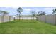 Grassy backyard with fence, view of the community pond, and lush landscaping at 10914 Penny Gale Loop, San Antonio, FL 33576