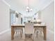 Bright dining room with view to modern kitchen featuring white cabinets, pendant lighting, and matching chairs at 120 Moscata Way, Nokomis, FL 34275
