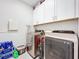 A laundry room features a front-load washer and dryer, overhead cabinets, and tile flooring at 120 Moscata Way, Nokomis, FL 34275