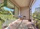 A covered patio with brick flooring features a sitting area surrounded by lush landscaping at 120 Moscata Way, Nokomis, FL 34275
