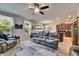 Bright living room featuring a ceiling fan, leather sofa, and a view of the kitchen with stainless steel appliances at 12328 Streambed Dr, Riverview, FL 33579