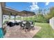 Outdoor patio with a dining table, umbrella, lounge seating, and brick pavers overlooking the lush, fenced backyard at 12328 Streambed Dr, Riverview, FL 33579
