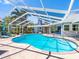 Inviting pool area enclosed with a screen, featuring lounge chairs and lush greenery for privacy at 13420 Rustic Pines S Blvd, Seminole, FL 33776