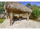 Outdoor tiki hut with seating area and lush landscaping creating a relaxing backyard oasis at 143 58Th S Ave, St Petersburg, FL 33705