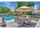 A table and chairs sit on a wooden deck with a landscaped backyard and an in-ground pool at 15112 Alexis Dr, Tampa, FL 33624