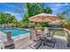 A table and chairs sit on a wooden deck with a landscaped backyard and an in-ground pool at 15112 Alexis Dr, Tampa, FL 33624