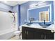 Bathroom with blue walls, stylish vessel sinks, bathtub, and shower combination at 16316 Silent Sands Ln, Odessa, FL 33556